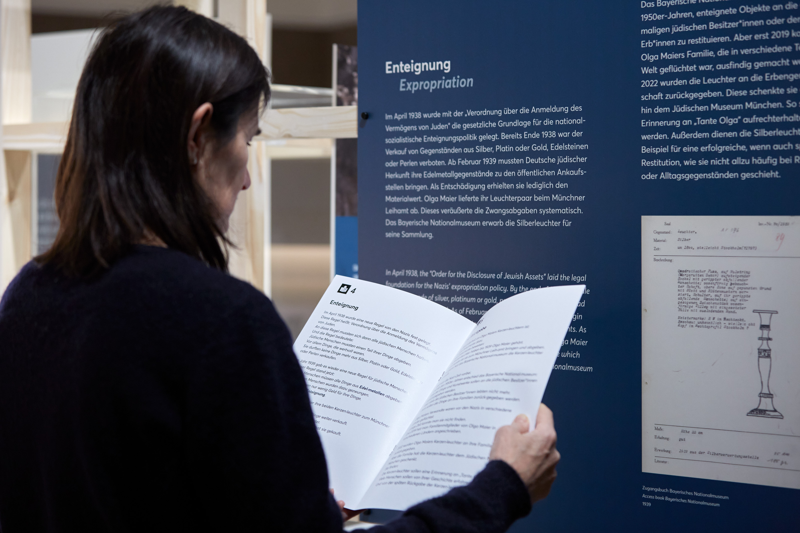 Visitor with an easy language brochure in the exhibition "Aunt Olga's Silver Candlestick. A Munich family history", photo Eva Jünger / Jewish Museum Munich 