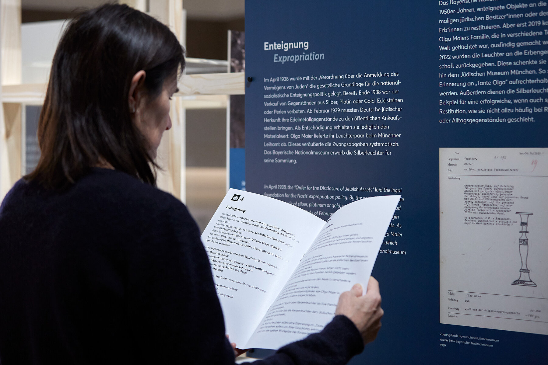 Besucherin mit Broschüre in Leichter Sprache in der Ausstellung "Tante Olgas Silberleuchter. Eine Münchner Familiengeschichte", Foto Eva Jünger / Jüdisches Museum München 
