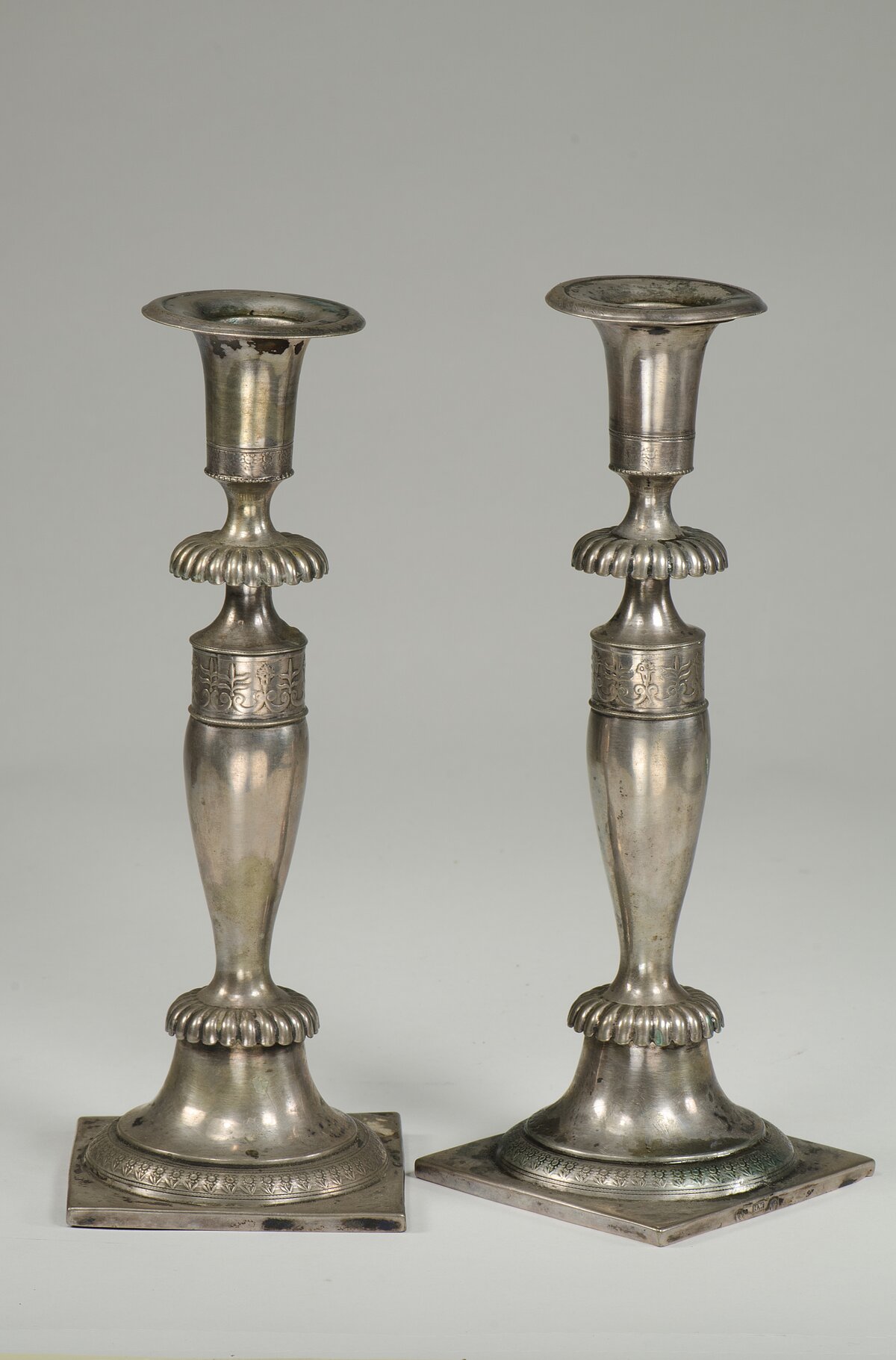 Two elaborately worked but simple silver candlesticks standing side by side, donated to the Jewish Museum Munich by the heirs of Olga Maier. 