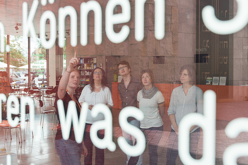 Rundgang im Jüdischen Museum, Foto: Daniel Schvarcz / JMM Bersucherbetreuerin mit Besucher*innen im Foyer des Jüdischen Museums