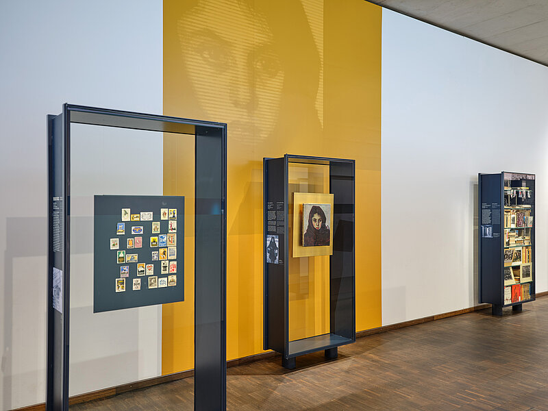 Ausstellungsansicht mit Studie zum Gemälde „Der Eltern Stütze“, Stanislaus Bender, vor 1919, Verweis in der Dauerausstellung mit gelbem Blowup an der Wand, Foto: Eva Jünger, © Jüdisches Museum München 