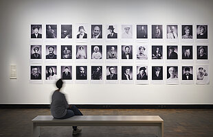 Ausstellungsansicht „Die Dritte Generation. Der Holocaust im familiären Gedächtnis“, mit Rafael Goldchain "I Am My Family", davor sitzend eine Besucherin. Foto: Eva Jünger / Jüdisches Museum München 