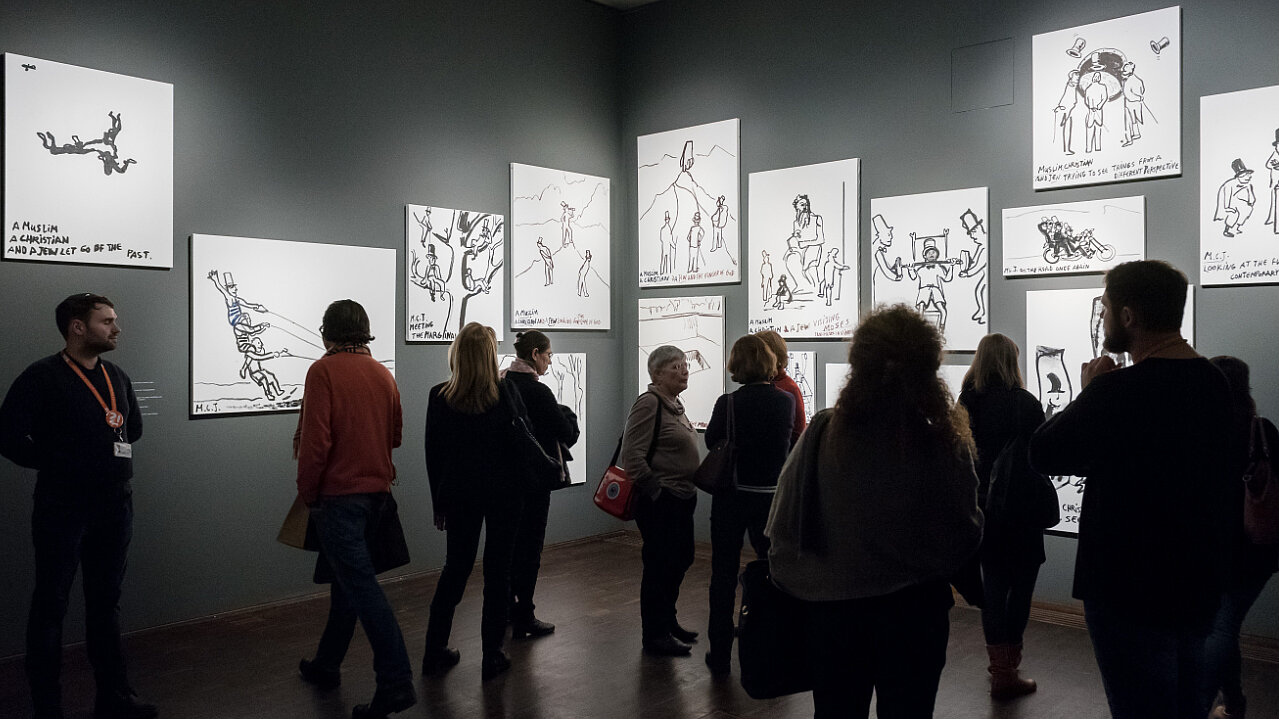Eine Besuchergruppe in der Ausstellung "A Muslim, a Christian and a Jew. Eran Shakine"