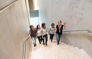 Rundgang „Unser Haus“Besucher*innen mit Besucherbetreuerin gehen die Treppe im Jüdischen Museum hinauf, Foto: Daniel Schvarcz 